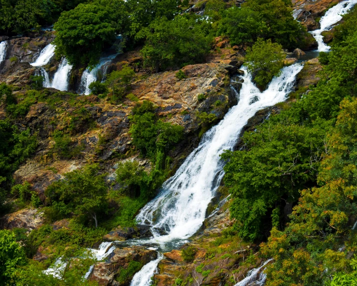 a view of several water streams and trees on a cliff