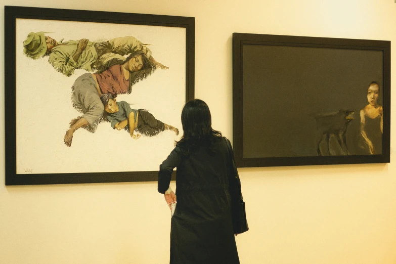 a woman looking at paintings hanging on the wall