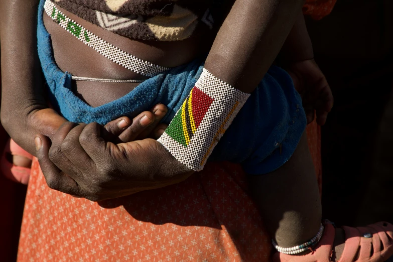 a woman has a baby wrapped in beads