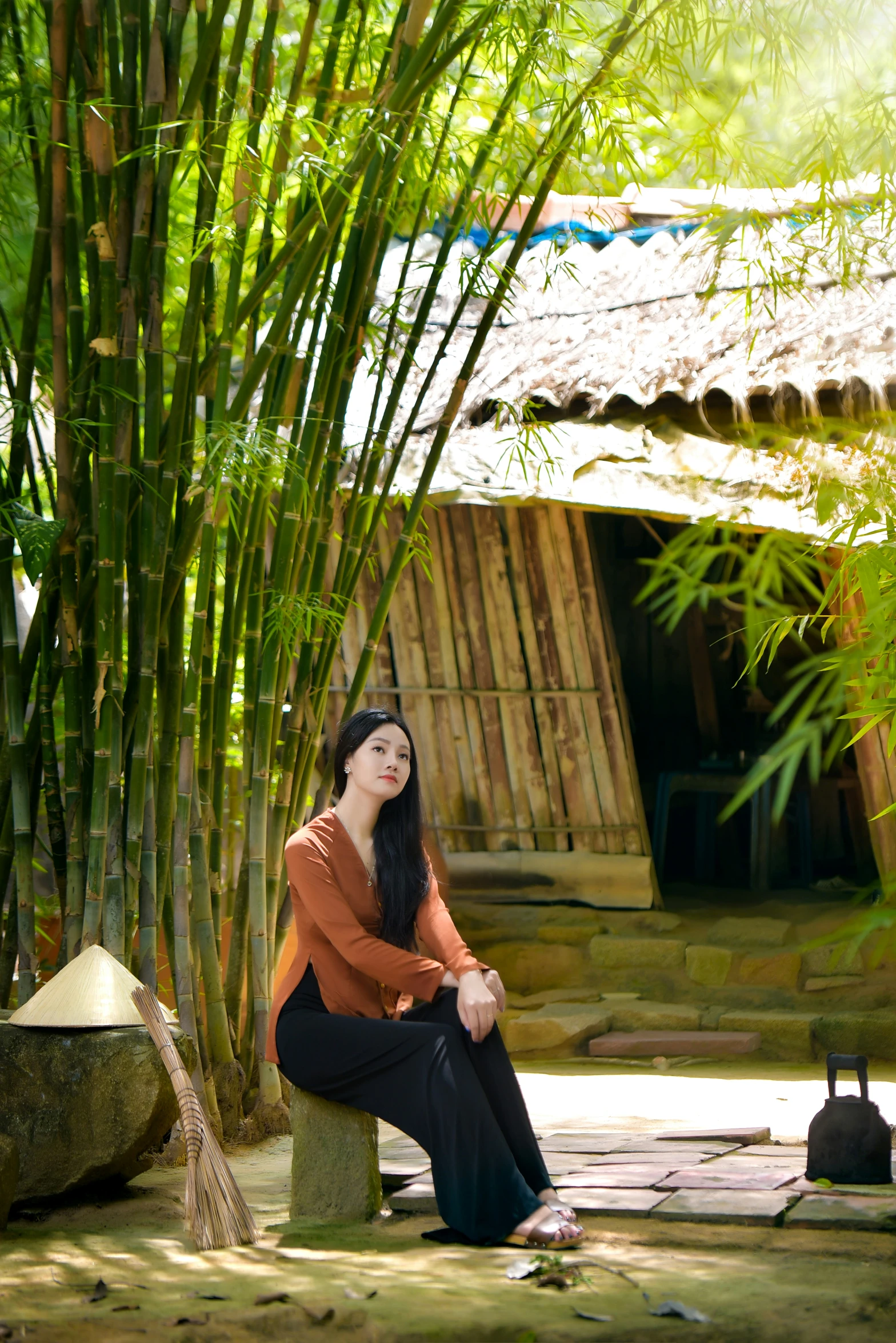 a woman that is sitting next to some bamboo trees