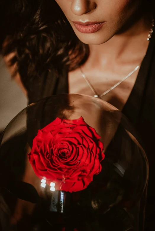 a woman holding a large red rose with pearls