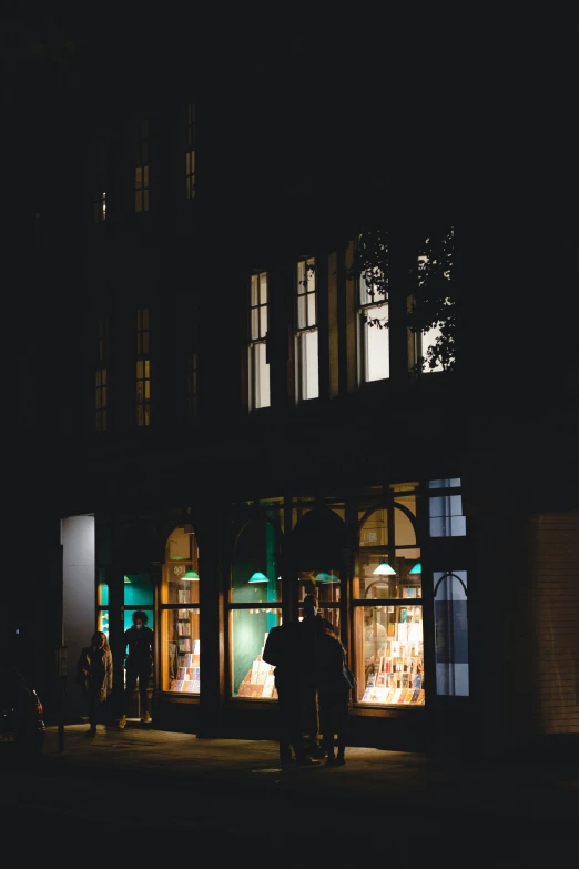 two people standing outside at night in front of a building