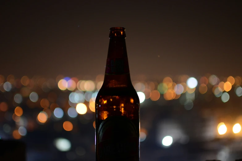 a beer bottle sits on a ledge with a city in the background