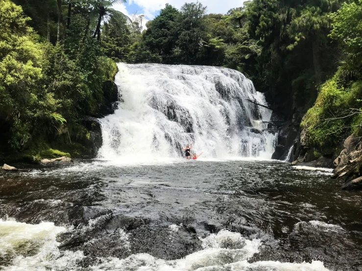 a person is kayaking in a lake near a waterfall