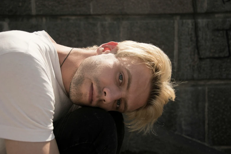 a man is leaning on a wall smiling at the camera