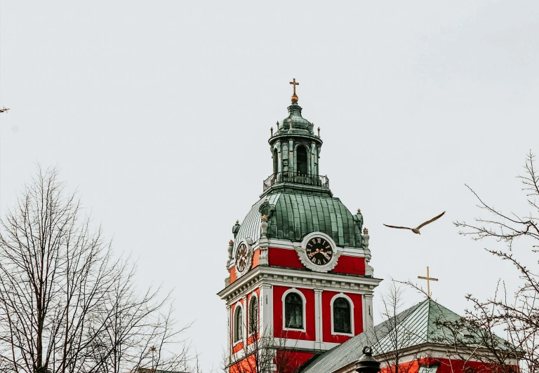 the clock is on the red and white tower