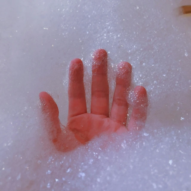 a hand poking out from some foam water