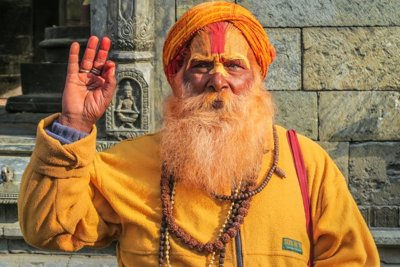 a man with an orange beard and red and yellow cloth on is waving