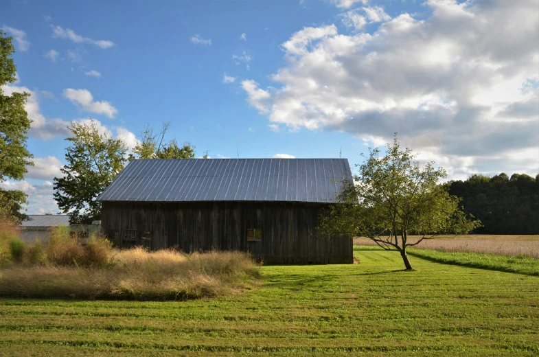 this old barn looks pretty in summer as the clouds loom over it