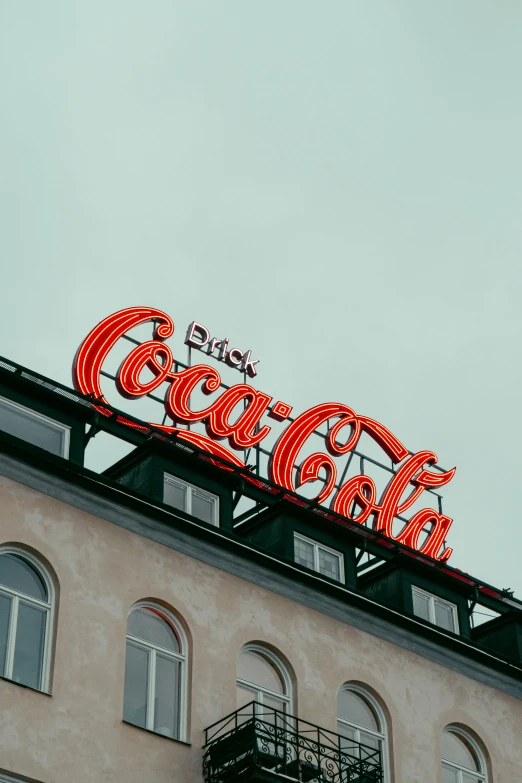 the neon coca cola sign on top of an old building