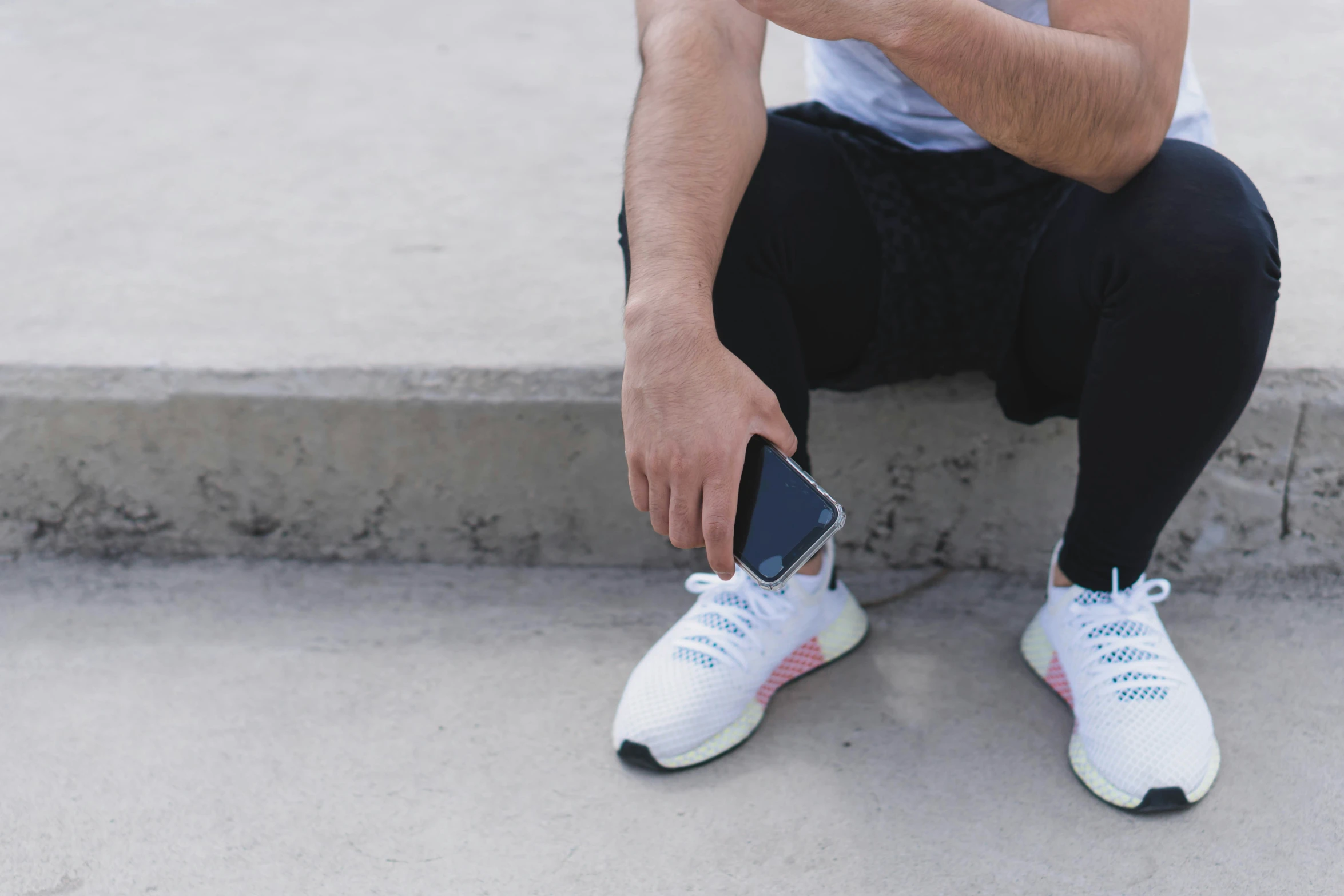 a young man is tying his shoes and holding the phone