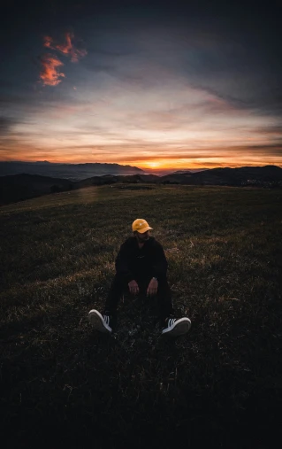 person sitting in a field, watching the sun set