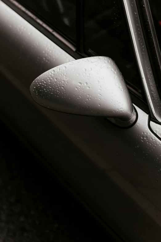 a car's door mirror is reflecting the back of a silver vehicle