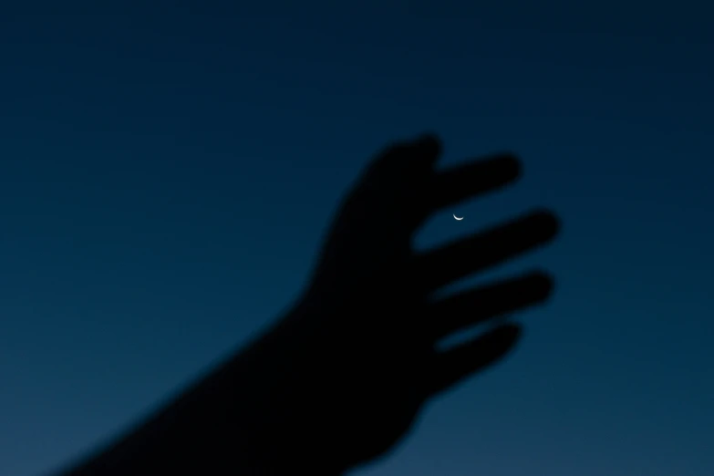 a hand holding a phone up towards a dark sky