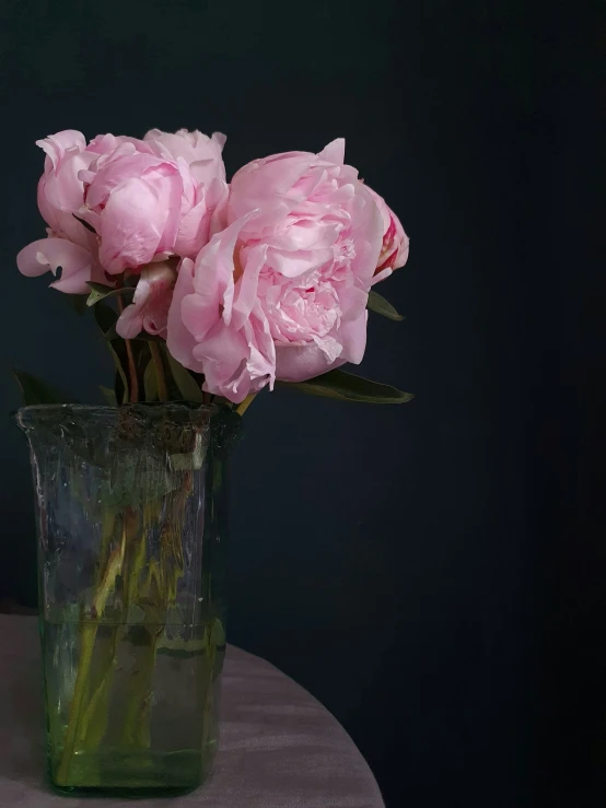 a couple pink flowers sitting in a green vase