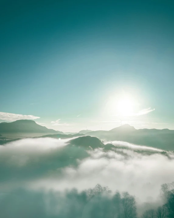 the sun is shining over mountains and low lying mist