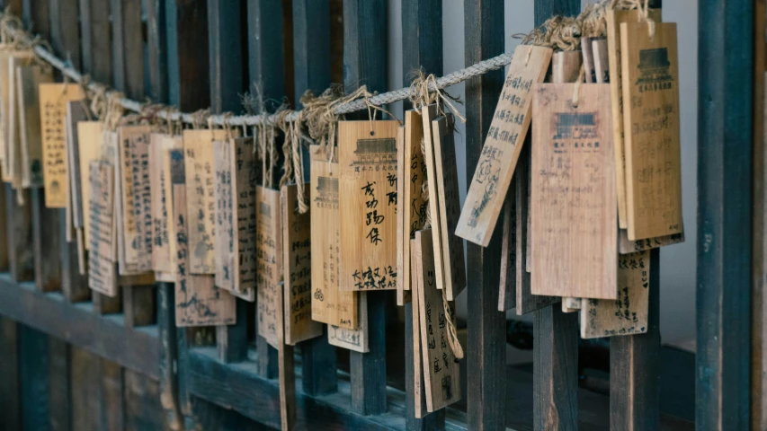 some small papers and some strings hanging from a fence