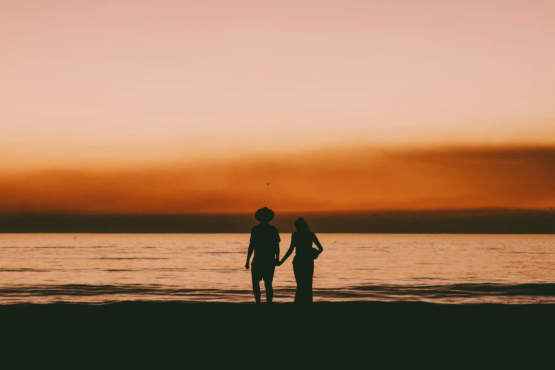 two people are standing at the beach watching the sky