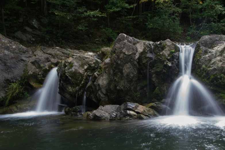 three waterfalls running over rocks in a river