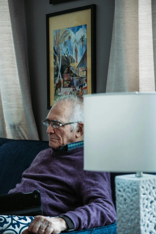 an elderly man on his laptop sits in a chair