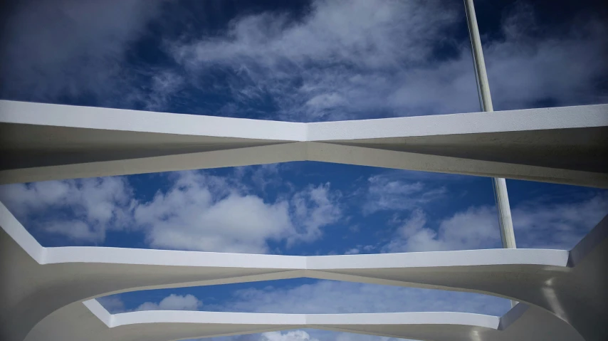 the top of a modern structure under a blue sky with clouds