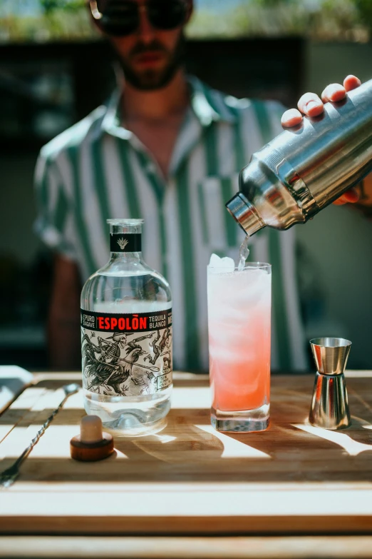 a bartender is holding a cocktail glass with the liquor in front of him