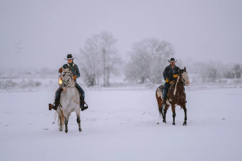 two men riding horses in the snow