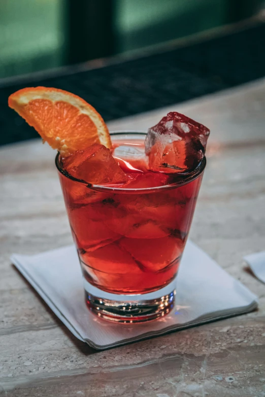 a glass filled with a drink and orange wedge