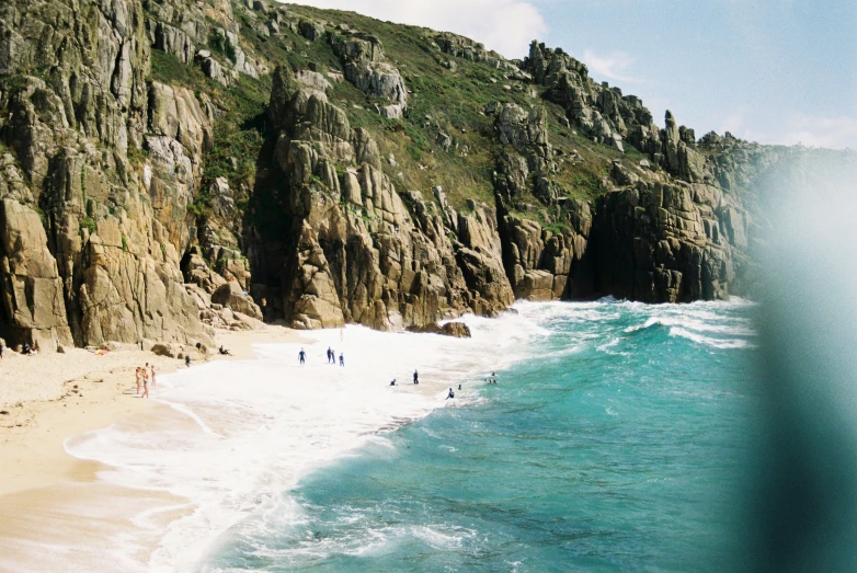 the people are walking down the beach near the mountains