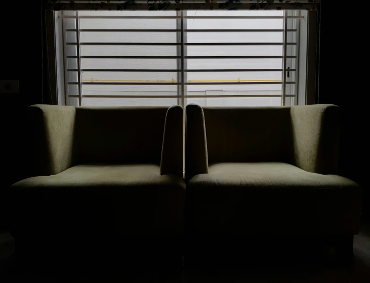 two chairs sit in the dark with a window behind them