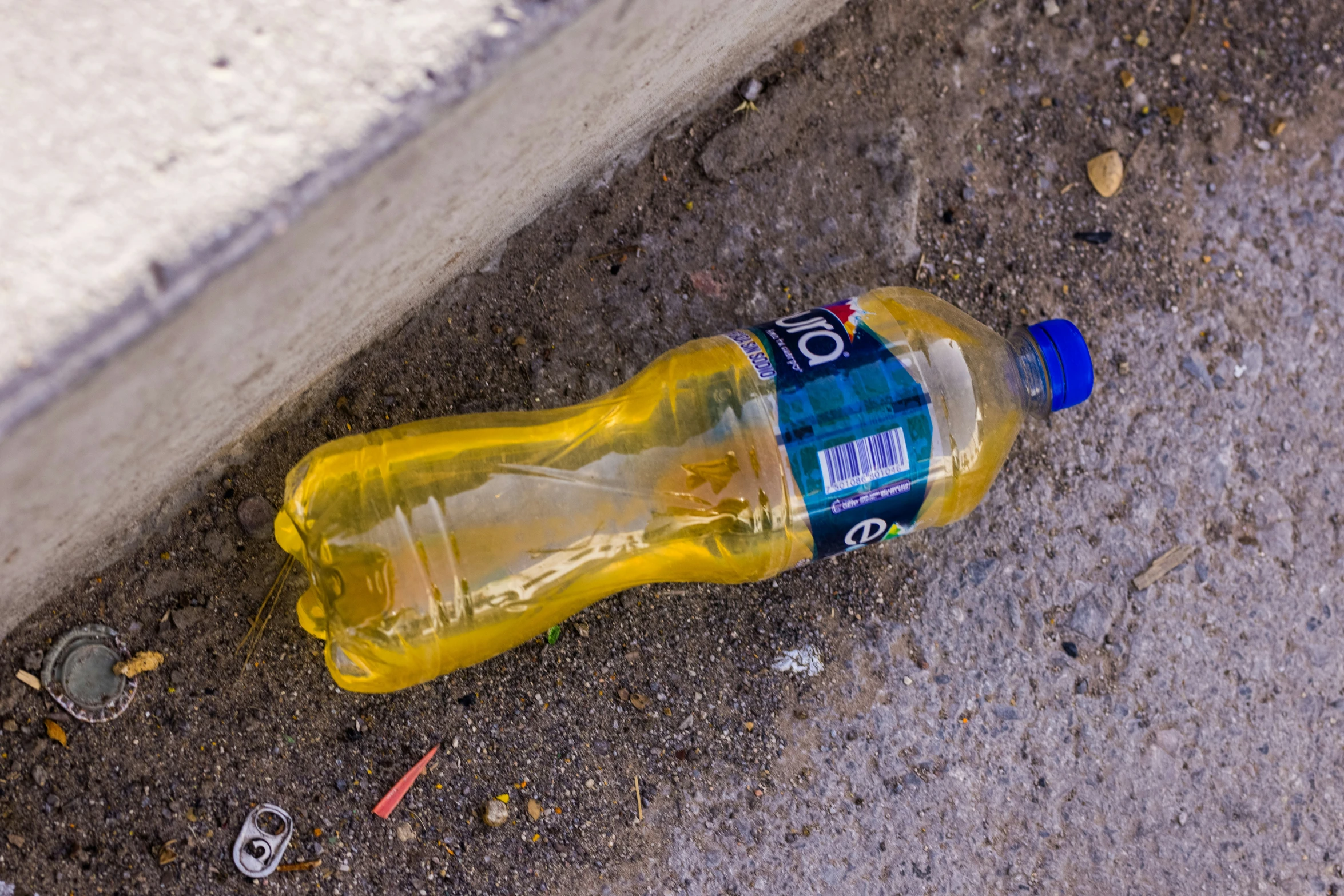 an empty bottled drink bottle on the ground near a curb