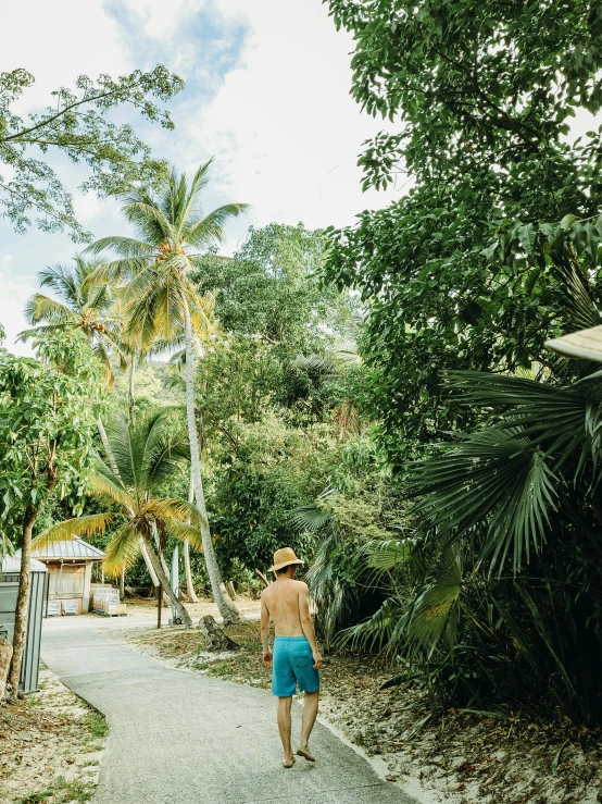 a man in blue trunks is walking down a path