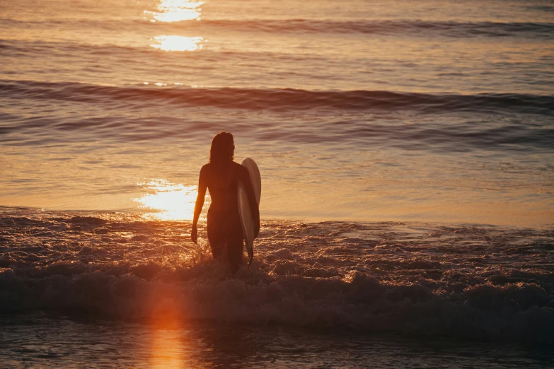 the person has a surfboard and walks into the water