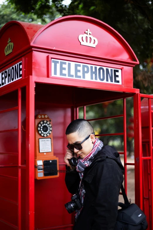 the man is standing in front of a red telephone booth