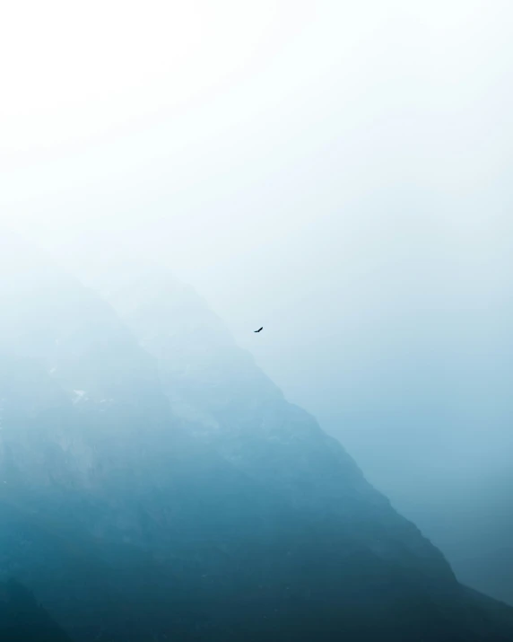 a plane is flying high in the sky over a mountain