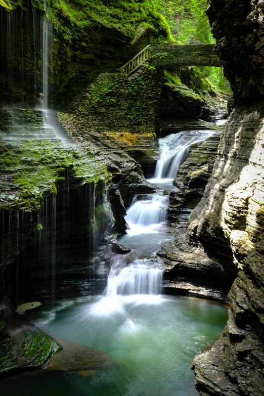 a group of waterfalls are surrounded by moss and water