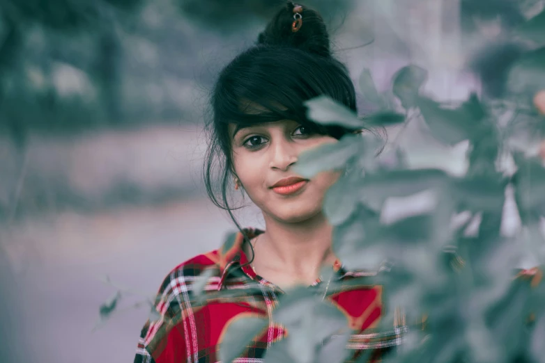 a woman standing near leaves, with her eyes closed