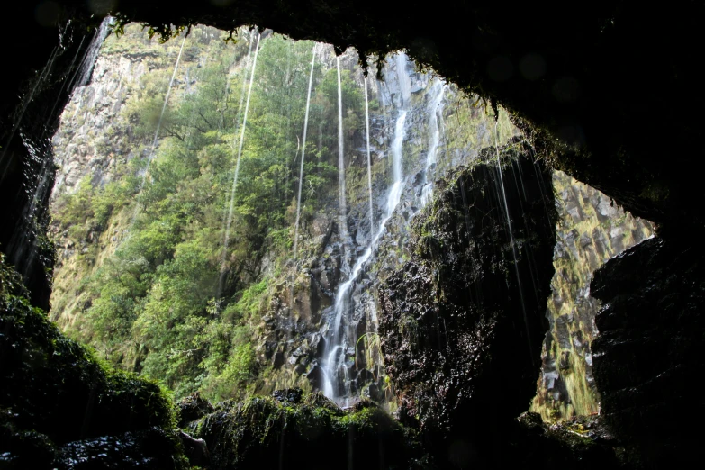 the view from underneath a waterfall is seen from a cave