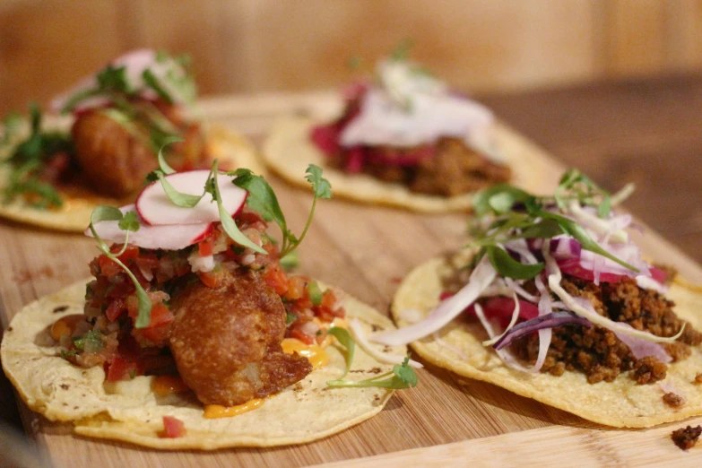 three tacos with meat and vegetables on it sitting on a board