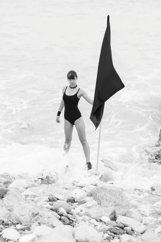 a woman wearing a bathing suit holding a flag in the ocean