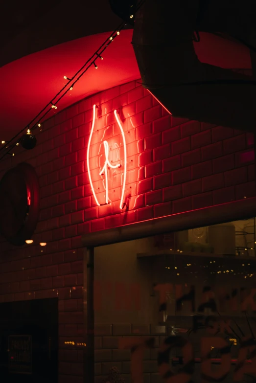 a red neon sign hanging from the side of a brick wall