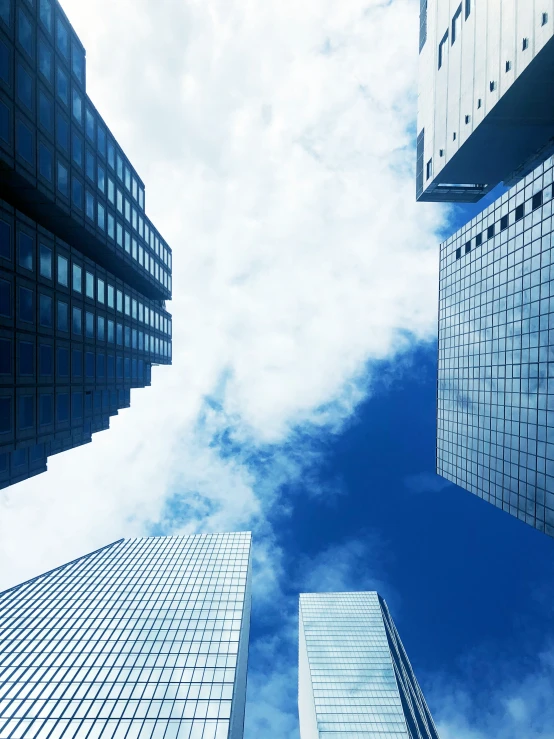 the view up at tall skyscrs against a cloudy blue sky