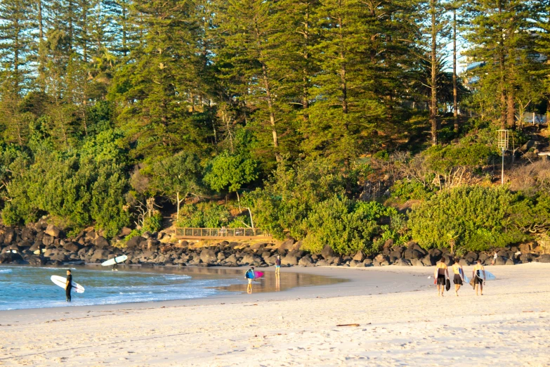 people walking along a sandy beach by the ocean