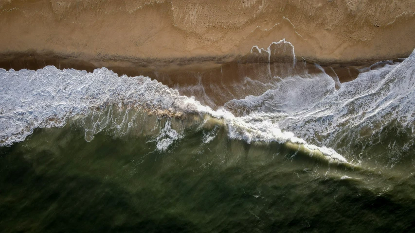 a large wave breaking over the top of some sand