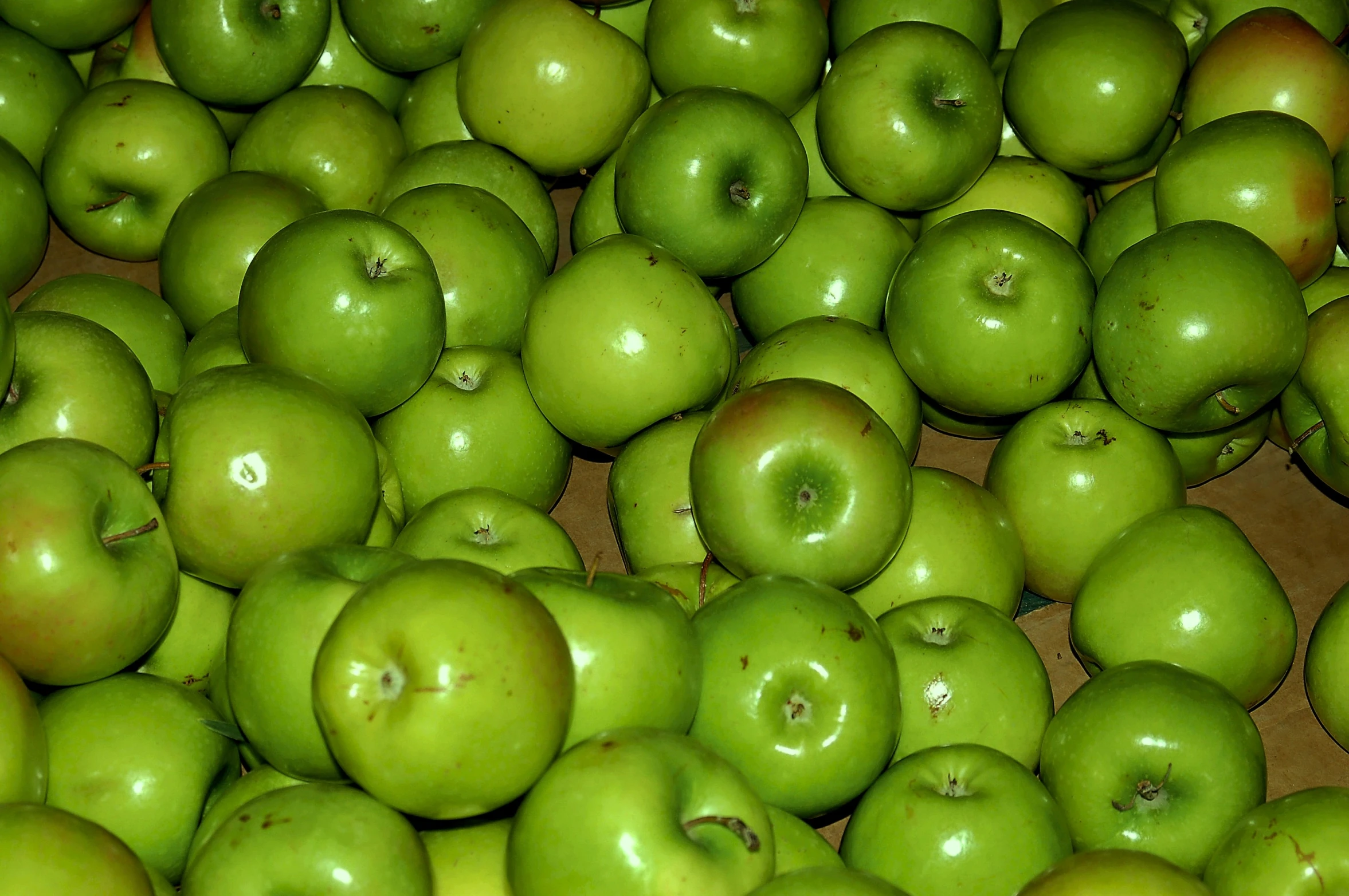 several rows of green apples are piled in a pile