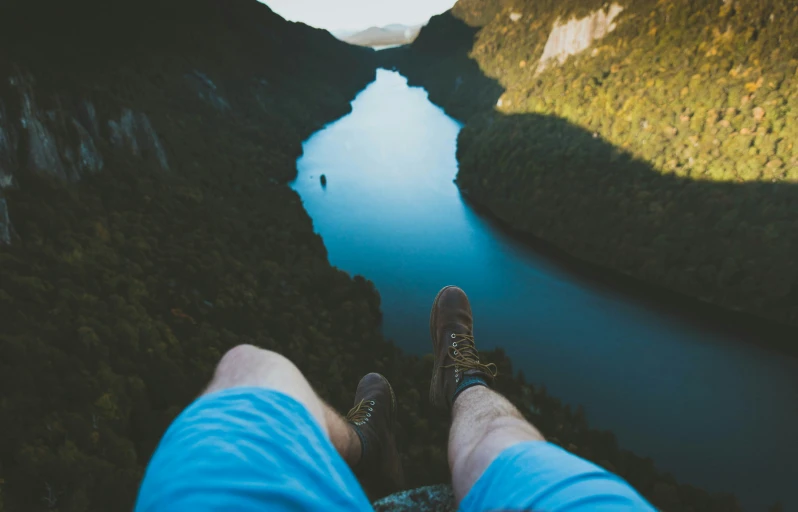 someone's feet point at a body of water and some mountains