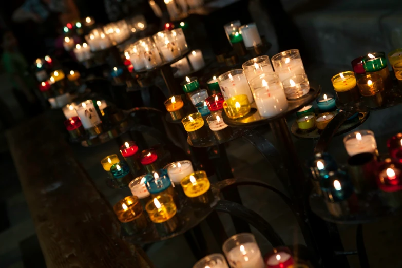 rows and rows of colorful lit candles on a table