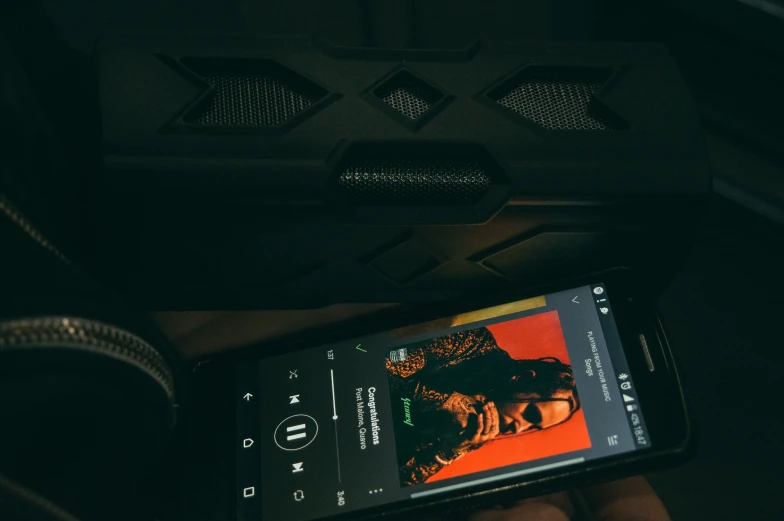 cell phone displaying artwork and music playing on screen