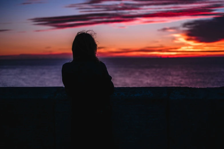 a person is sitting down looking at the sunset