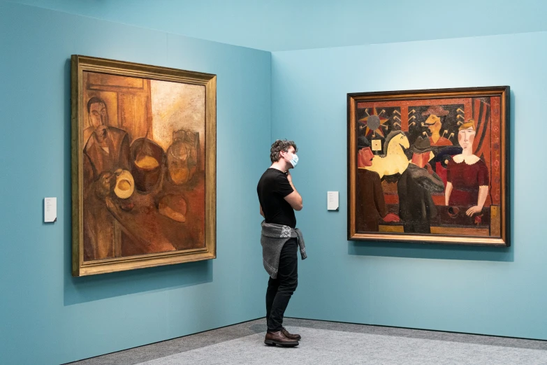 a person in black shirt standing in front of paintings